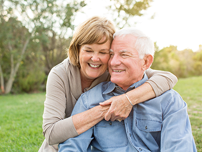 An elderly couple sharing an affectionate moment outdoors.