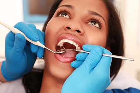 A woman receiving dental care with a dentist performing the procedure.