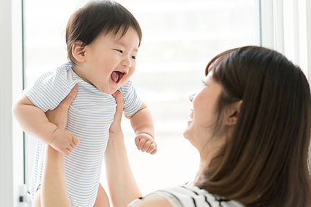 The image depicts a woman holding a baby who appears to be laughing.