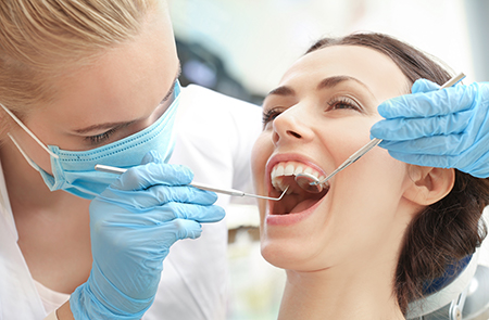 The image shows a dental professional performing dental work on a patient s mouth using specialized equipment.